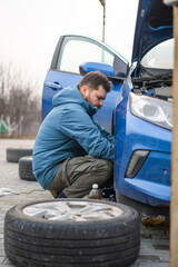A man changes the brake fluid in a blue car