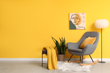 Interior of living room with rocking armchair, plant and lamp