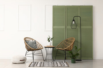 Interior of living room with armchairs, table and folding screen