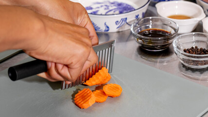 A hand of Asian descent crafting crinkle-cut carrots, evoking autumn equinox rituals and vibrant...