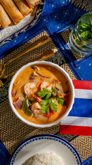 Aromatic Tom Yum soup with shrimp dazzles beneath tropical sunlit tapestry, perfect for Songkran celebration or eclectic culinary retreat