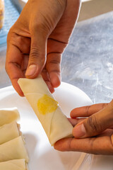 Crafting delectable spring rolls with precise fingers, Asian female chef prepares for Lunar New...