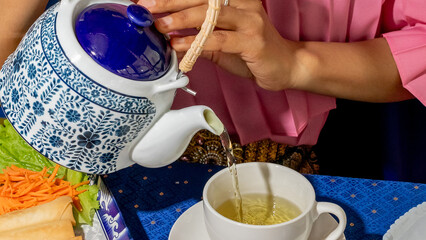 Pouring jasmine tea into a porcelain cup, capturing serene calmness, Lunar New Year, meditative...