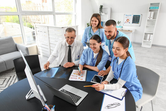 Group of medical interns with doctor at table in clinic