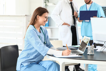 Female medical intern writing at table in clinic