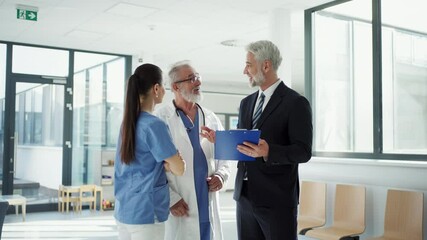 Medical sales representative presenting new medication to doctors, standing hospital hallway. - Powered by Adobe