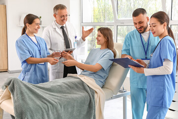 Medical interns giving pills and glass of water to patient in clinic