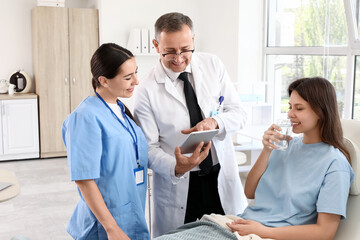 Female medical intern and doctor working with patient in clinic