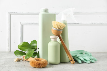 Set of natural cleaning supplies with plant branch on table near light wall