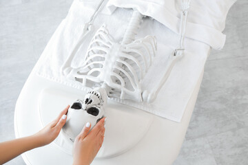 Female hands massaging human skeleton on couch in spa salon, top view