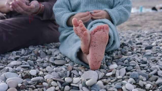 Footprints on pebbled beach during family outing in early evening light