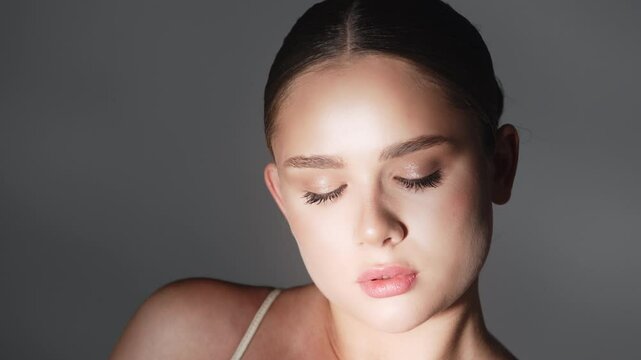 Close-up of a beautiful woman with glowing skin posing in a studio in dim lighting. Ideal for beauty, skincare and cosmetics advertising.