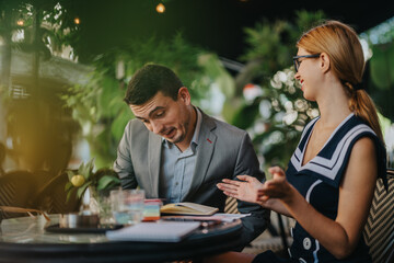 Two businesspeople discussing sales strategies in an outdoor setting. They analyze reports and...