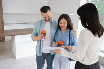 Female real estate agent showing house plan to couple in kitchen