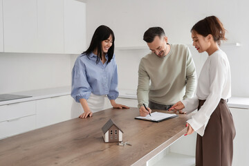 Female real estate agent with couple signing agreement in kitchen