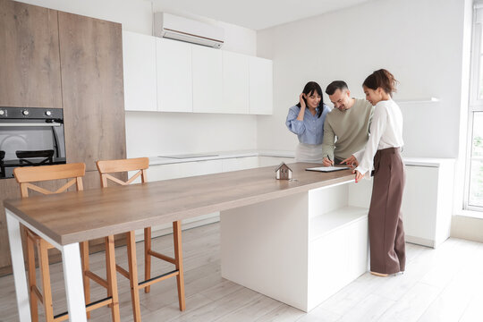 Female real estate agent with couple signing agreement in kitchen