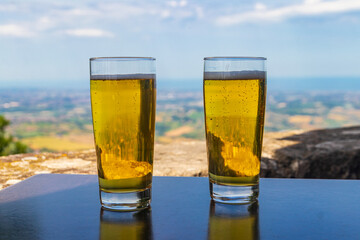 Two glasses of beer on a table with a view of San Marino