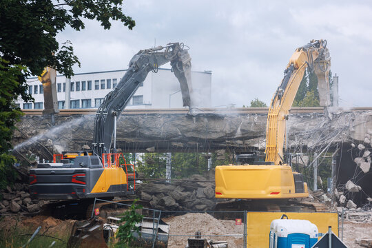 Close-up view of crumbling bridge structure demolition in Magdeburg Damaschkeplatz exposed steel rebar falling concrete chunks. Rubble piles and demolition machinery emphasize destruction progress