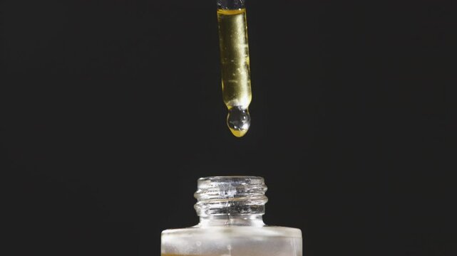 Mockup of glass bottle with dropper cap in female hands. Amber container with cosmetic product, serum on isolated background in sunlight. Beauty concept.
