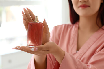 Young woman with perfume in bathroom, closeup