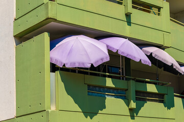 Charming balconies adorned with pastel umbrellas offer a colorful view of urban life in a vibrant...