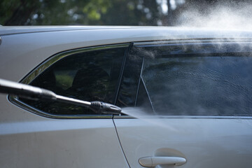 Fototapeta premium washing a dirty car and wheels with water and a pressure washer