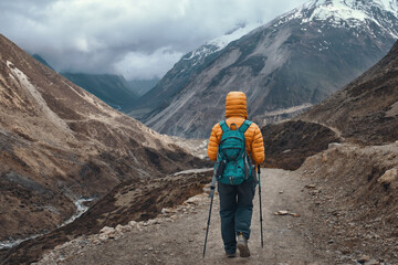 Hiker walks along mountains trail against picturesque mountain valley during Manaslu Circuit trek in Himalayas, Nepal.