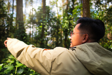 Man Pointing Towards the Distance in a Sunlit Forest Setting