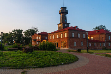Old red brick fire station with wooden gates and observation tower
