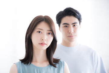 夏服のカップルのカメラ目線のクローズアップ　白背景　真剣な表情と不穏な離婚や倦怠期のようなイメージ