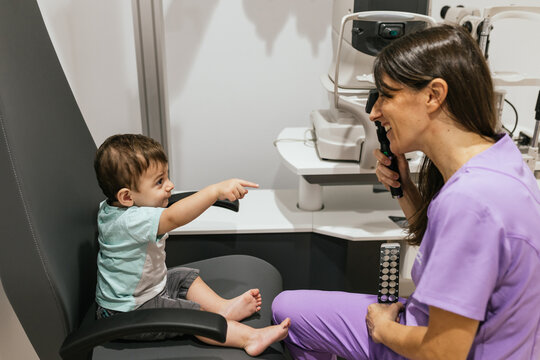 Optometrist doing eyesight test on a baby boy in her office - Powered by Adobe