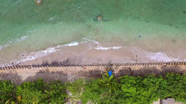 Aerial view showing a beach with turquoise waters, sandy shoreline, and patches of green vegetation