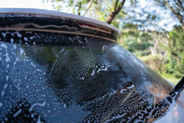 washing a dirty car and wheels with water and a pressure washer