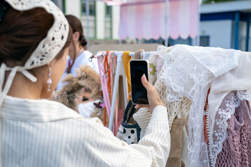 A young woman is trying on a handmade knitted crochet headscarf at the street market. Delicate,...