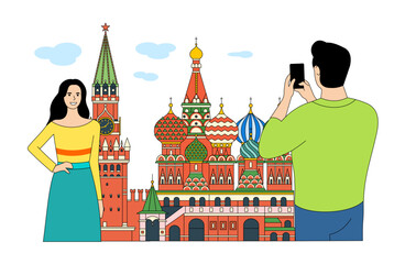 A guy takes a photo of a girl against the backdrop of the Kremlin and St. Basil's Cathedral in Moscow.