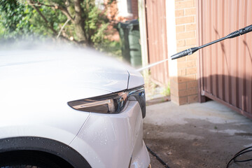 washing a dirty car and wheels with water and a pressure washer
