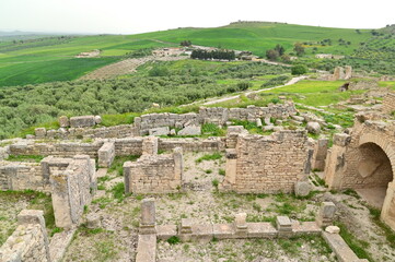 View of Roman Ruins in Dougga with Broken Stone Walls and Open Countryside Landscape in Tunisia