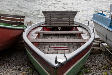 A charming green-red boat rests by the shore, its bow pointing toward the shimmering water