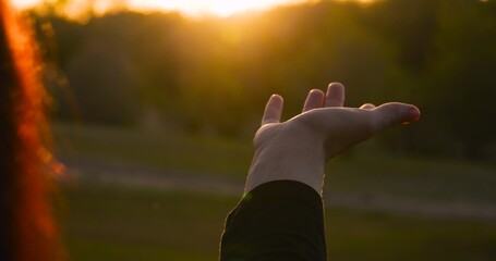 woman hand reaches out sunlight against natural backdrop, expressing freedom, hope and harmony....