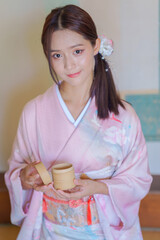 Young Asian Japanese woman in a Traditional Yukata Dress. Asian girl wearing a beautiful pink...