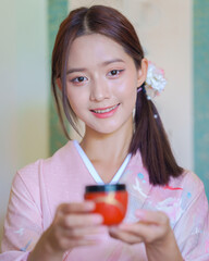 Young Asian Japanese woman in a Traditional Yukata Dress. Asian girl wearing a beautiful pink...