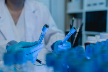 Fototapeta premium a female scientist is working in lab, a chemist tests liquid sample in science laboratory, she wears a lab coat when she works in laboratory, test tube, scientific equipment