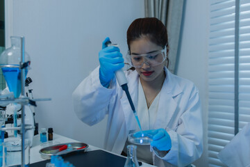 a female scientist is working in lab, a chemist tests liquid sample in science laboratory, she...