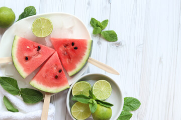 Ripe watermelon pieces on sticks like ice cream. Watermelon, lime and mint. Summer fruits...