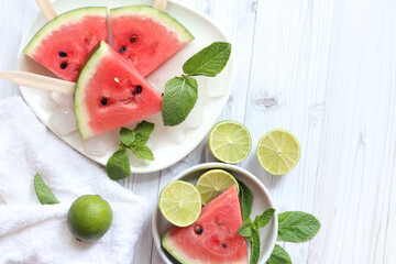 Ripe watermelon pieces on sticks like ice cream. Watermelon, lime and mint. Summer fruits...