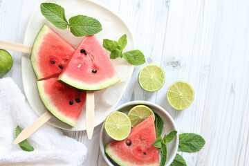 Ripe watermelon pieces on sticks like ice cream. Watermelon, lime and mint. Summer fruits...
