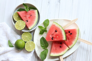 Ripe watermelon pieces on sticks like ice cream. Watermelon, lime and mint. Summer fruits...