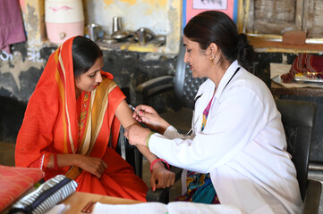 Indian female doctor taking injection to rural woman at dispensary. Rural woman vaccination in india