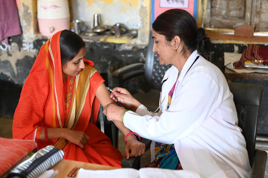 Indian female doctor taking injection to rural woman at dispensary. Rural woman vaccination in india