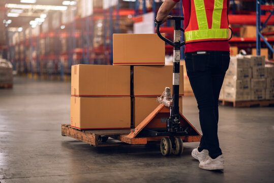 Factory Worker, Close Up Hands Using Hand Pallet Truck to Move Carton Box in Logistics and Distribution Center